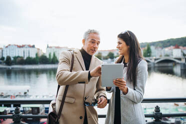 Mann und Frau Geschäftspartner mit Tablet stehen an einem Fluss in der Stadt Prag, im Gespräch. - HPIF28414