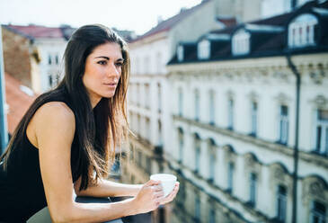 Glückliche junge Geschäftsfrau mit einer Tasse Kaffee auf einer Terrasse in einem Büro in der Stadt. - HPIF28435