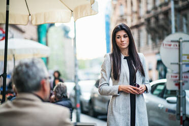 Eine attraktive Geschäftsfrau steht im Freien auf einem Bürgersteig in einer Stadt. Raum kopieren. - HPIF28447