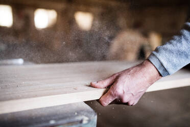 Die Hand eines nicht zu erkennenden Mannes, der in der Schreinerei mit Holz arbeitet. - HPIF28518