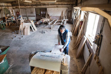 Ein älterer Mann arbeitet in einer Schreinerei mit Holz, Ansicht von oben. - HPIF28520