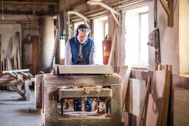 Ein erwachsener Mann arbeitet in einer Schreinerei mit Holz. - HPIF28523