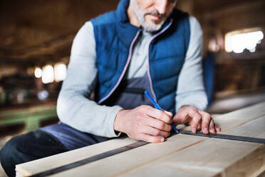 Ein unkenntlicher älterer Mann arbeitet in der Schreinerei mit Holz. - HPIF28530