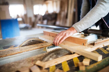 An unrecognizable man worker in the carpentry workshop, working with wood. - HPIF28542