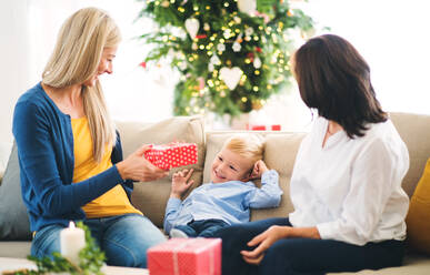 Eine Mutter und eine Großmutter beschenken einen kleinen Jungen zu Hause zur Weihnachtszeit. - HPIF28562