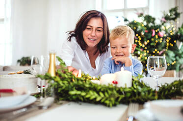 Ein glücklicher kleiner Junge mit seiner Großmutter, der zur Weihnachtszeit zu Hause am Tisch sitzt. - HPIF28583