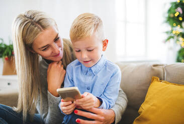 A mother and small boy with smartphone sitting on a sofa at home at Christmas time, playing games. - HPIF28594