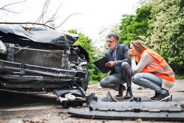 An insurance agent and a woman driver looking at the car on the road after an accident. Copy space. - HPIF28606