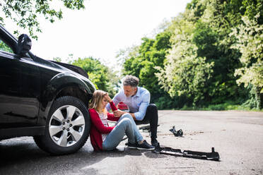 Junge Frau am Auto nach einem Unfall und reifer Mann, der ihr hilft. - HPIF28630