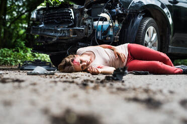 Young injured woman lying in blood on the road, unconscious. A car accident concept. Copy space. - HPIF28639