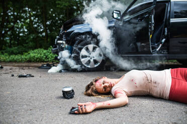 Young injured woman lying on the road, unconscious. A car accident concept. Copy space. - HPIF28643