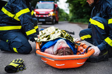 Eine junge verletzte Frau in einer Kunststofftrage nach einem Autounfall, zugedeckt mit einer Wärmedecke, Nahaufnahme. - HPIF28665