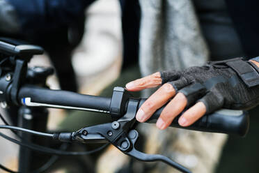 Nahaufnahme einer weiblichen Hand auf dem Lenker eines Elektrofahrrads im Freien in einem Park. - HPIF28686