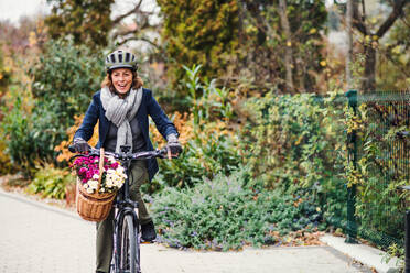 Aktive Seniorin mit Helm und Elektrofahrrad beim Radfahren im Freien in der Stadt. Raum kopieren. - HPIF28710