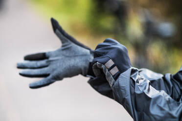 Nahaufnahme eines Radfahrers, der im Freien in einem Park schwarze Handschuhe anzieht. - HPIF28763