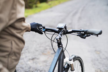 A midsection of an unrecognizable cyclist with electrobike standing outdoors in town. - HPIF28781