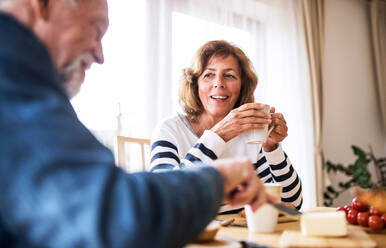 Älteres Ehepaar beim Frühstück zu Hause: Ein alter Mann und eine alte Frau sitzen am Tisch und frühstücken. - HPIF28822