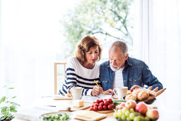 Ein älteres Ehepaar frühstückt zu Hause, ein alter Mann und eine alte Frau sitzen am Tisch und entspannen sich. - HPIF28830