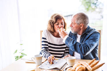 Älteres Ehepaar beim Frühstück zu Hause: Ein alter Mann und eine alte Frau sitzen am Tisch und frühstücken. - HPIF28831
