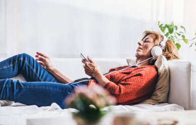 Senior woman relaxing at home, listening to music. - HPIF28846