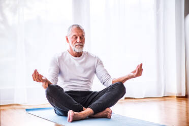 Aktiver älterer Mann meditiert zu Hause, Augen geschlossen. - HPIF28867