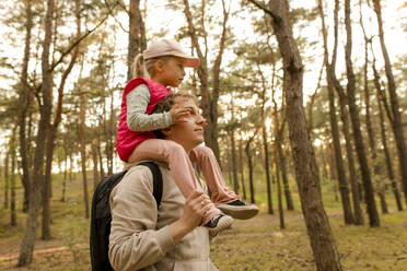 Father carrying daughter on shoulder in forest - VIVF00942