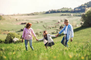Älteres Paar mit Enkelin draußen in der Natur im Frühling, lachend. - HPIF28938