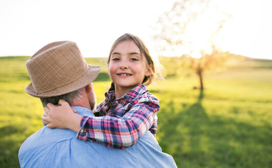 Ein fröhliches kleines Mädchen mit Großvater draußen in der frühlingshaften Natur, das Spaß hat. Raum kopieren. - HPIF28984