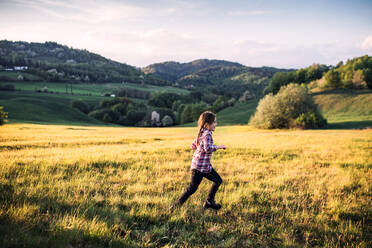 Ein glückliches kleines Mädchen, das draußen in der Natur Spaß hat und läuft. - HPIF29015