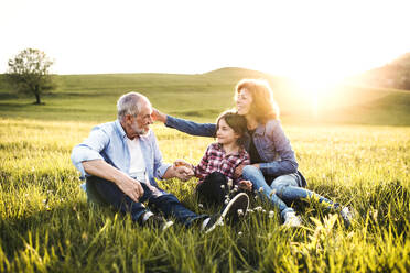 A senior couple with granddaughter outside in spring nature at sunset. - HPIF29018