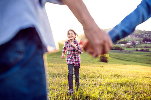 Ein glückliches kleines Mädchen mit ihren nicht wiederzuerkennenden älteren Großeltern, die draußen in der Natur Spaß haben. - HPIF29029