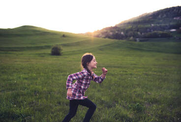 Ein glückliches kleines Mädchen, das bei Sonnenuntergang draußen in der Natur herumläuft. Raum kopieren. - HPIF29038