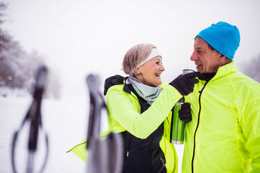 Aktives Seniorenpaar beim Skilanglauf, ein Mann und eine Frau trinken heißen Tee, Winterzeit. - HPIF29057