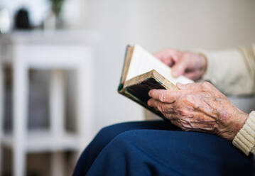 A close-up of hands and knees of senior woman reading Bible at home. - HPIF29061