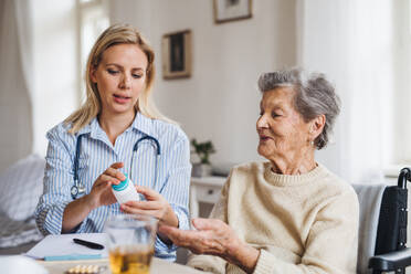 Eine junge Gesundheitsberaterin erklärt einer älteren Frau im Rollstuhl, wie man Medikamente und Tabletten einnimmt. - HPIF29089