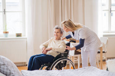 A young health visitor talking to a senior woman in wheelchair at home. - HPIF29103