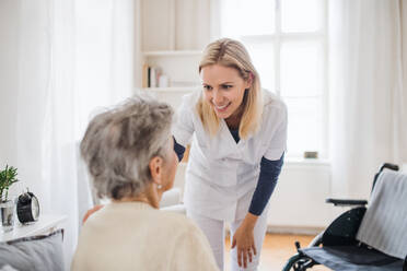 Eine Gesundheitsberaterin im Gespräch mit einer nicht erkennbaren älteren Frau, die zu Hause im Bett sitzt. - HPIF29106