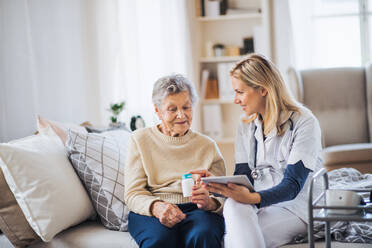 A young health visitor explaining a senior woman how to take medicine and pills. - HPIF29123