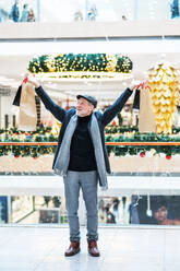 Senior man doing Christmas shopping. Shopping center at Christmas time. - HPIF29169