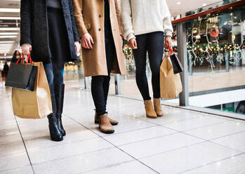 Unbekannte junge Freunde mit Taschen, die zur Weihnachtszeit in einem Einkaufszentrum spazieren gehen. - HPIF29219