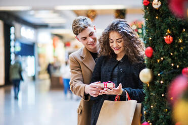 A happy young man giving a present to his girfriend in shopping center at Christmas time. Copy space. - HPIF29225