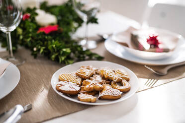 Gingerbread biscuits on a table set for a dinner at home at Christmas time. - HPIF29292