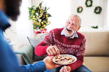 Ein unkenntlicher Mann, der seinem älteren Vater zu Hause zu Weihnachten Kekse schenkt. - HPIF29324