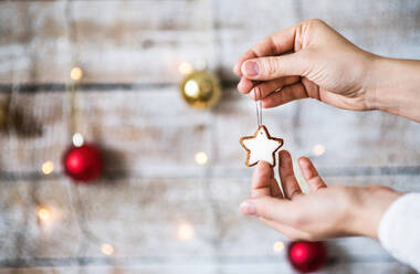 Weibliche Hand, die Weihnachtsschmuck hält, ein sternförmiges Gebäck an einer Schnur, Kopierraum. - HPIF29417