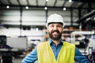 A portrait of a happy industrial man engineer in a factory. - HPIF29491