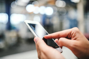 Close-up of female hands in a factory using smartphone. Copy space. - HPIF29522