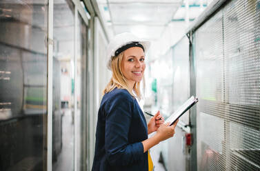 Das Porträt einer jungen Ingenieurin in einer Fabrik, die etwas überprüft. - HPIF29528