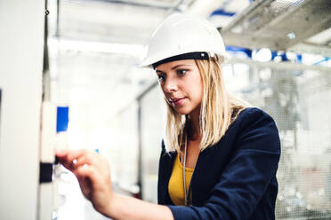 Das Porträt einer jungen Ingenieurin in einer Fabrik, die etwas überprüft. - HPIF29530