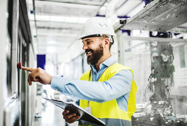 Porträt eines reifen Industrieingenieurs mit Klemmbrett in einer Fabrik, bei der Arbeit. Raum kopieren. - HPIF29545