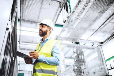 Porträt eines reifen Industrieingenieurs mit Klemmbrett in einer Fabrik, bei der Arbeit. Raum kopieren. - HPIF29546